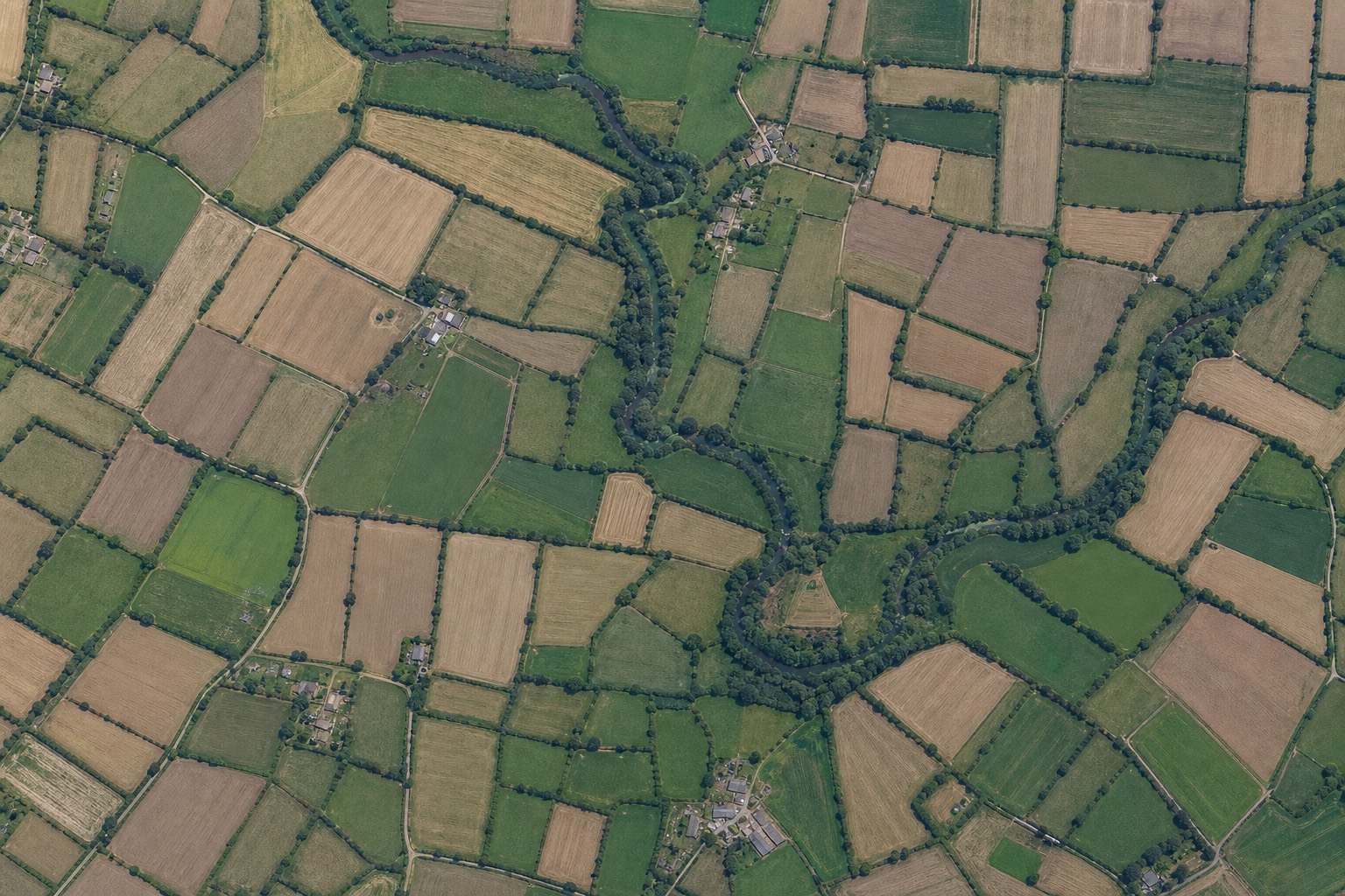 Vue aérienne verticale d'un paysage de bocage français : parcelles cultivées, haies, rivière